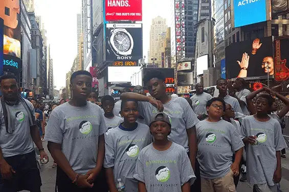 Group of youths in matching t-shirts standing in Times Square, New York City.